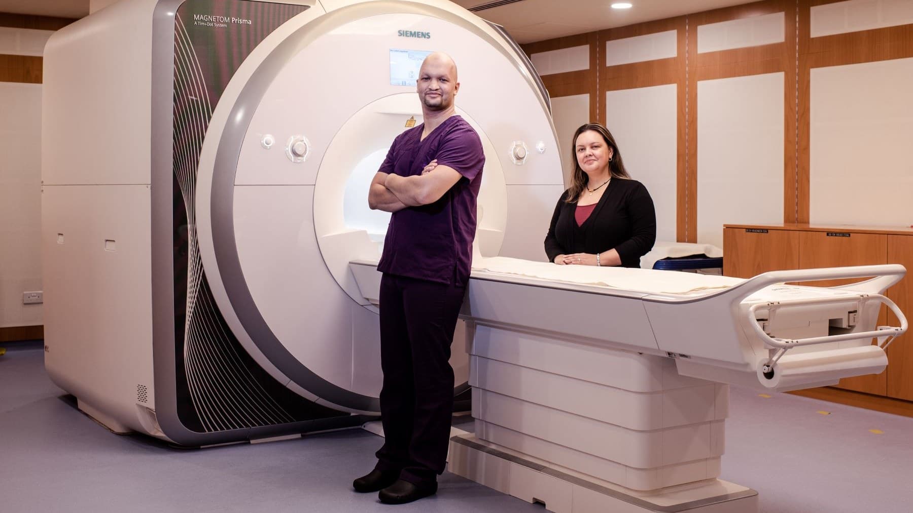 Dr Osama Abdullah and a colleague standing beside the MRI scanner at NYU Abu Dhabi